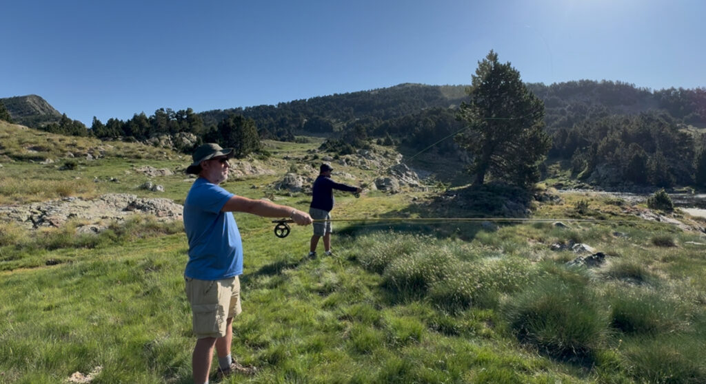 Deux pêcheurs s'entraînent au lancer à la mouche dans une prairie de montagne